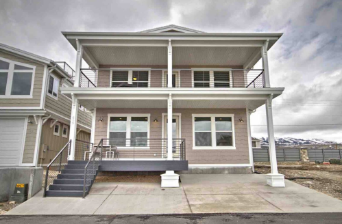 A modern two-story house with a porch, large windows, and a staircase, set against a cloudy sky.