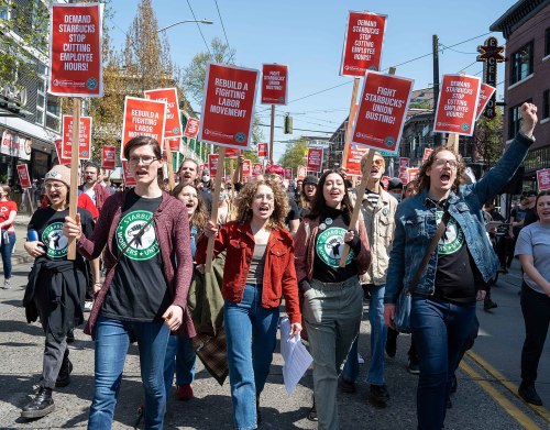A group of protesters march with signs demanding better labor conditions at Starbucks, expressing solidarity and activism.
