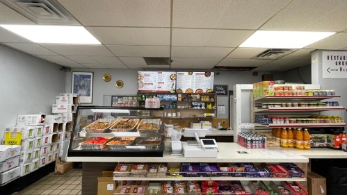 A food counter displaying various dishes, drinks, and snacks in a casual dining setting.