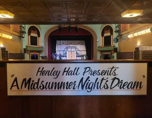 A stage set for "A Midsummer Night's Dream" at Henley Hall, with a decorative backdrop and lighting.