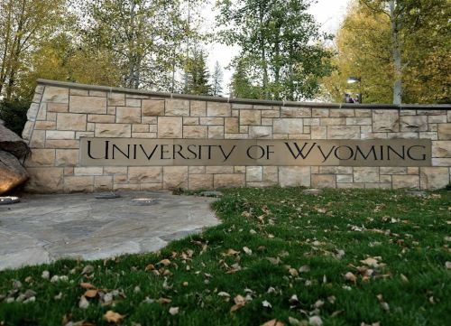 Sign for the University of Wyoming, set against a backdrop of trees and grass.