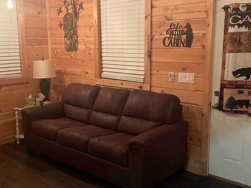 Cozy cabin interior featuring a brown couch, wooden walls, and decorative wall art.