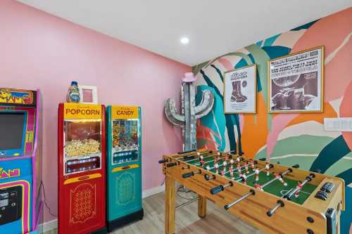 A vibrant game room featuring a foosball table, popcorn and candy machines, and colorful wall art.