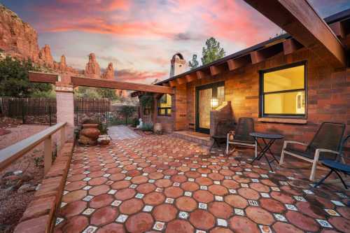 A cozy patio with tiled flooring, surrounded by nature and a colorful sunset sky in the background.