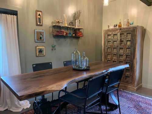 A rustic dining area featuring a wooden table, black chairs, and decorative shelves with vintage items on the walls.