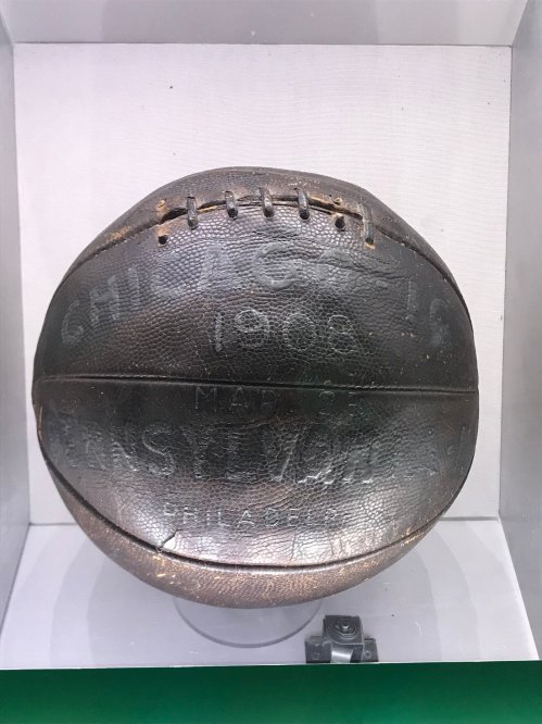A vintage basketball from 1906, displayed in a case, featuring the inscription "Chicago 1906 Made in USA."