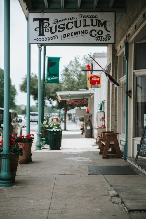 A charming street view in Boerne, Texas, featuring Tusculum Brewing Co. and colorful storefronts.