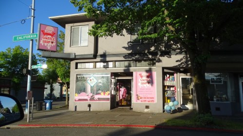 A storefront with a sign reading "Waffle Shop," featuring large windows and colorful decorations outside.