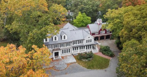 Aerial view of a large house surrounded by colorful autumn trees and a nearby red barn-style garage.