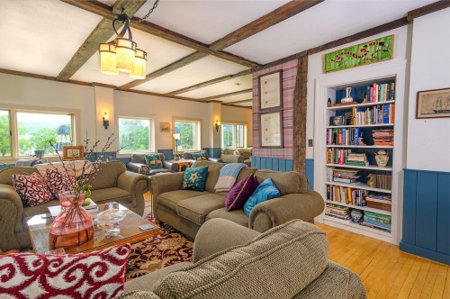 Cozy living room with comfortable sofas, a bookshelf, and large windows letting in natural light.