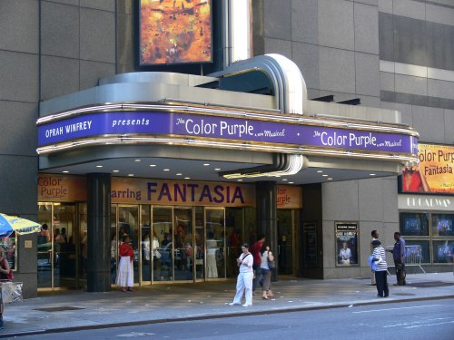 Theater marquee for "The Color Purple" musical, featuring Fantasia, with people entering and walking by.