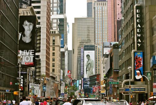 A bustling Times Square with tall buildings, large advertisements, and crowds of people on the streets.