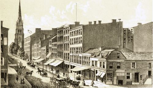 Historic street scene with horse-drawn carriages, buildings, and a church steeple in the background.