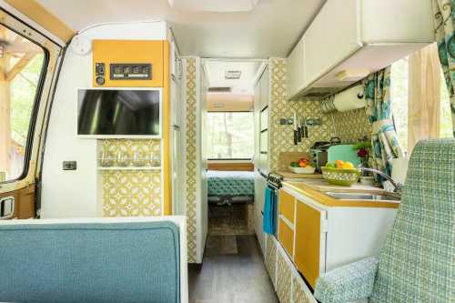 Interior of a cozy camper van featuring a kitchenette, seating area, and a view of a bedroom in the background.