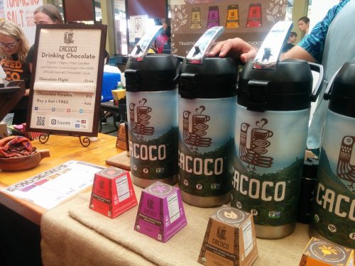 A display of Cacoco drinking chocolate with containers and a sign promoting chocolate flights and a special offer.