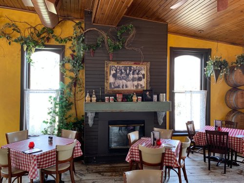 Cozy restaurant interior with checkered tablecloths, a fireplace, and vintage decor on yellow and dark walls.