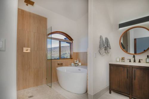 Modern bathroom featuring a freestanding tub, glass shower, wooden accents, and a scenic window view.