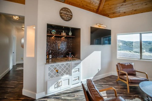 Modern interior featuring a kitchenette with a wine rack, wooden accents, and a scenic view through a large window.