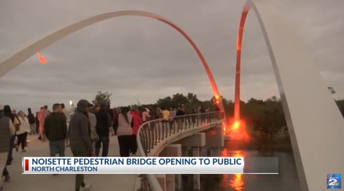 Crowd gathers for the opening of Noisette Pedestrian Bridge in North Charleston, with dramatic lighting in the background.