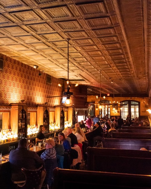 A cozy restaurant interior with a bar, dim lighting, and patrons enjoying their meals in a warm atmosphere.