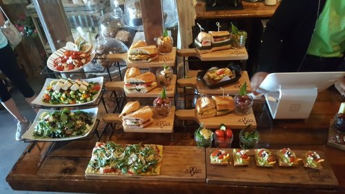 A display of various gourmet sandwiches, salads, and appetizers on wooden platters in a rustic setting.