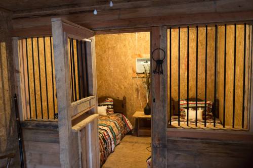 A rustic room with two beds separated by bars, featuring wooden walls and simple decor.