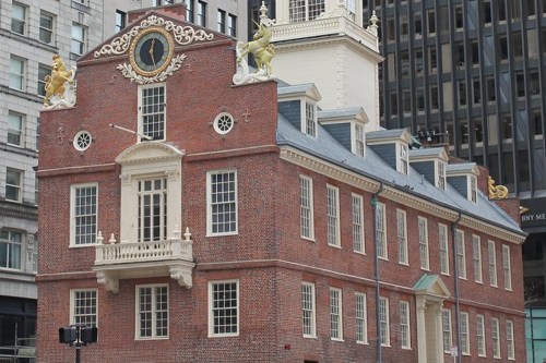 Historic brick building with ornate details and a clock, featuring golden lion sculptures on the roof.
