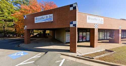 Exterior view of a brick building with "Breathe It In Salt Rooms" signage, surrounded by trees and a parking area.