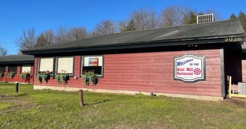 Exterior of the Grist Mill Restaurant, featuring a wooden facade and flower boxes under the windows.