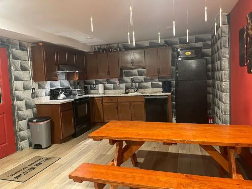A modern kitchen with dark wood cabinets, stainless steel appliances, and a wooden picnic table in a cozy dining area.