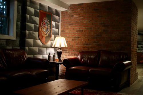 Cozy living room with leather sofas, a wooden coffee table, and a lamp, featuring a brick wall and decorative banner.