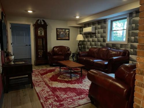Cozy living room with leather sofas, a wooden coffee table, a vintage clock, and a patterned rug.