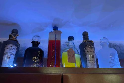 A collection of decorative potion bottles on a shelf, illuminated with blue light.