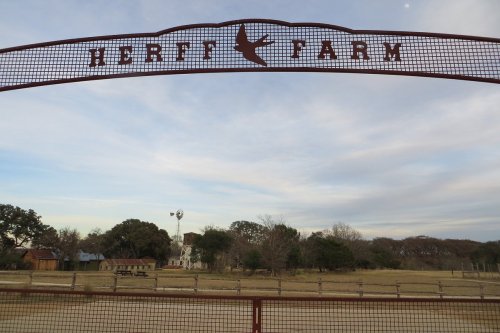 A metal sign reading "Secret Farm" above a rustic landscape with a windmill and scattered trees under a cloudy sky.