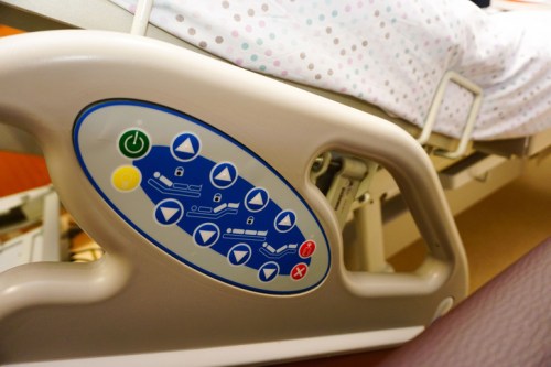 Close-up of a hospital bed control panel with buttons for adjusting position and settings.