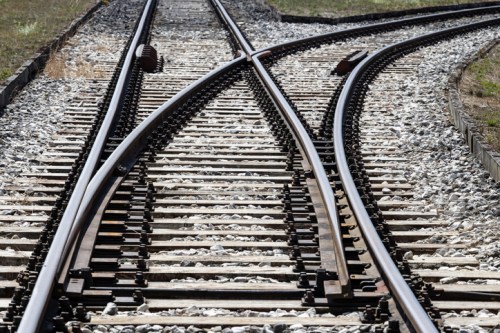 Two sets of railway tracks intersecting, with gravel and wooden ties visible along the sides.
