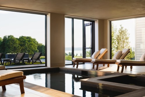 A serene spa area with lounge chairs, large windows, and a view of a tranquil outdoor landscape and water.