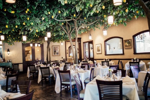A cozy restaurant with tables set for dining, featuring trees with lemons and warm lighting.