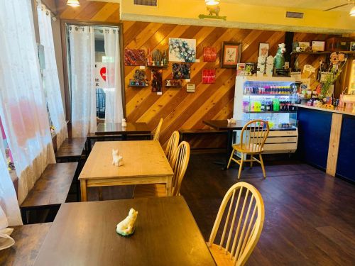 Cozy café interior with wooden tables, chairs, and colorful decor on the walls, featuring a vibrant counter area.