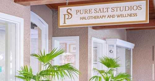 Sign for Pure Salt Studios, featuring "Halotherapy and Wellness," surrounded by indoor plants.