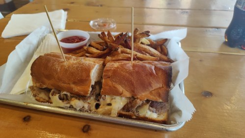 A tray with two sandwiches and a side of fries, accompanied by a small bowl of ketchup.
