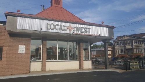 Exterior of a restaurant named "Locke & Key" with a metal roof and large windows, set against a blue sky.