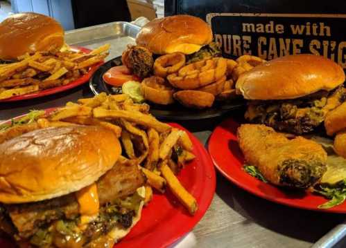 A variety of burgers and sides, including fries and onion rings, served on red plates.