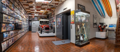 A hallway lined with music memorabilia, featuring a vintage car display and guitars in glass cases.