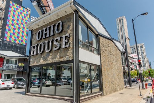 Exterior view of Ohio House, a stone building with large windows, located on a city street with tall buildings in the background.