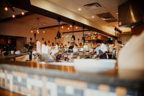 A bustling restaurant interior with chefs at work, warm lighting, and a vibrant atmosphere.