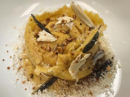 A beautifully plated dish of pasta topped with herbs, nuts, and cheese, garnished with delicate slices.