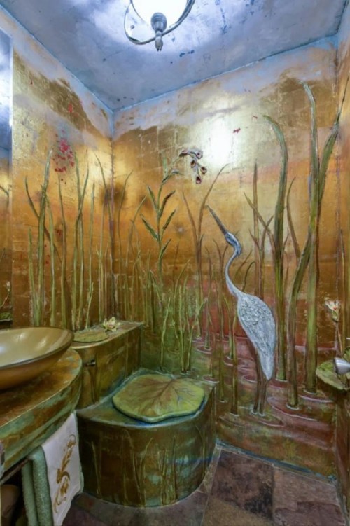 A uniquely designed bathroom with gold-toned walls featuring embossed plants and a heron, creating a serene atmosphere.