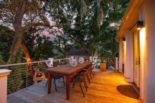 A cozy outdoor dining area with a wooden table and chairs, surrounded by trees and soft evening lighting.