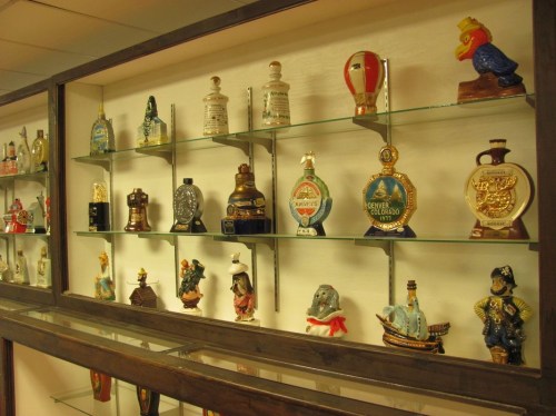 A display case filled with various decorative bottles and figurines arranged on glass shelves.
